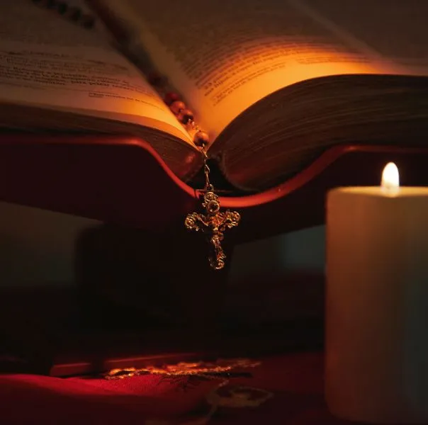 Hands holding a rosary and a candle during Knights of Columbus morning prayer